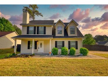 Charming two-story home with black shutters, a covered porch, landscaped yard, and fresh green grass at 1700 Conductor Ln, Conyers, GA 30013