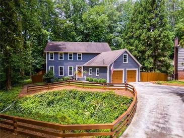 Charming blue two-story home with a well-manicured lawn, inviting curb appeal, and attached two car garage at 7250 Hunters Branch Dr, Atlanta, GA 30328