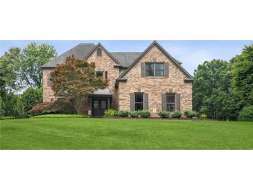 Elegant brick home with a well-manicured lawn and mature landscaping offers classic curb appeal at 1800 Hunters Moon Dr, Alpharetta, GA 30005