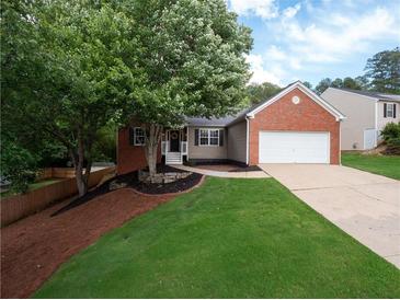 Charming single-Gathering home with well-manicured lawn, mature trees, brick accents, and an attached garage at 803 Plantation Ridge Overlook, Woodstock, GA 30188