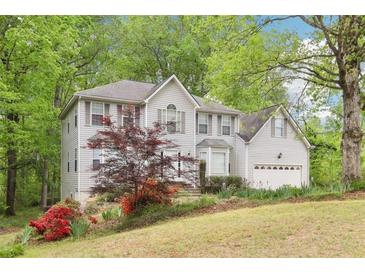 Charming two-story home with light siding, a well-manicured lawn, and mature trees at 6230 Lillie Ln, Cumming, GA 30040