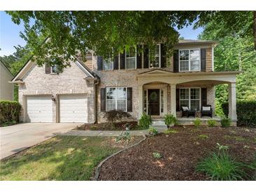 Charming two-story brick home with a covered front porch, two-car garage, and well-manicured lawn at 5828 Paliser Trce, Sugar Hill, GA 30518