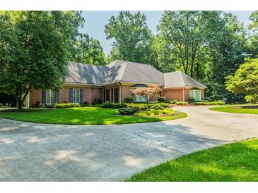 Charming brick home with a circular driveway and well-manicured lawn, shaded by mature trees at 3030 Spalding Dr, Sandy Springs, GA 30350