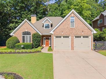 Charming brick home featuring a manicured lawn and an attached two-car garage at 7615 Abbey Glen Dr, Cumming, GA 30028