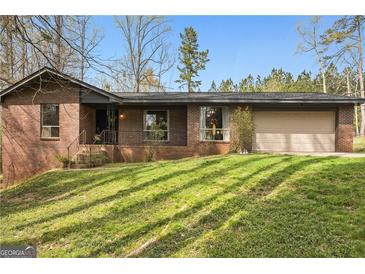 Charming brick home with attached garage and spacious front yard with healthy green grass at 779 Pinehurst Dr, Fairburn, GA 30213