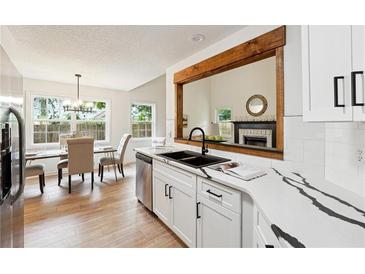 Modern kitchen features white cabinets, stainless appliances, a wood-framed cutout, and gorgeous countertops at 6 Stonebridge Se Ct, Cartersville, GA 30121