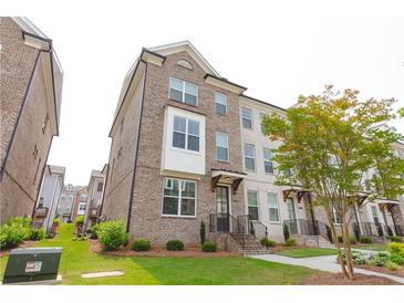 Charming three-story brick townhome with well-maintained landscaping and inviting front entrance at 3195 Bartee Walk, Suwanee, GA 30024