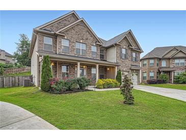 Charming two-story brick home with a well-manicured lawn and blooming flower beds at 5445 Whisper Ct, Cumming, GA 30028