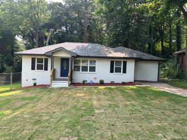 Charming single-story home featuring a freshly landscaped front yard, white brick exterior and an attached garage at 2349 Ousley Ct, Decatur, GA 30032