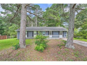 Charming single-story home featuring a gray brick exterior, a small front porch, and mature shade trees at 62 Sunny Ln, Villa Rica, GA 30180