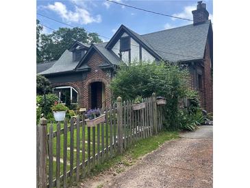 Charming brick home featuring a well-maintained lawn, picket fence with flowers, and an inviting arched entryway at 451 S Columbia Dr, Decatur, GA 30030