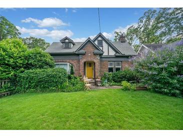Charming brick Tudor-style home featuring a well-manicured lawn and lush greenery in a desirable neighborhood at 451 S Columbia Dr, Decatur, GA 30030