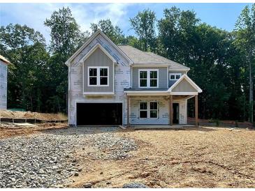 New home construction with grey siding, dark garage door, and covered porch surrounded by trees at 731 Crest Line Trl, Powder Springs, GA 30127