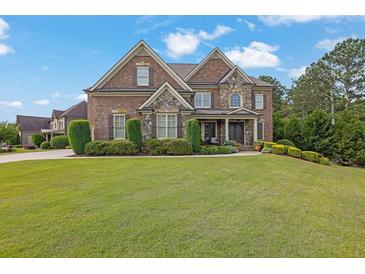 Charming brick home featuring manicured lawn, stone accents, and a meticulously landscaped front yard at 2450 Weber Heights Way, Buford, GA 30519