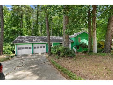 Charming green two-car garage home nestled among mature trees offering natural light and privacy at 5760 Windermere Ct, Lithonia, GA 30038