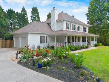 Charming two-story home featuring a welcoming front porch, well-manicured lawn, and vibrant flower beds at 2820 Channing Way, Cumming, GA 30040
