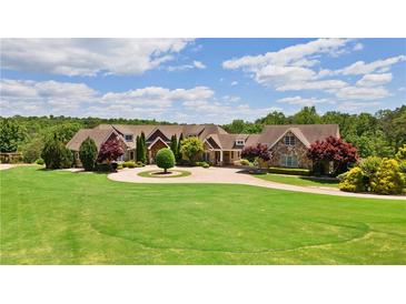 Expansive front lawn and circular driveway leading to a custom home with mature trees at 2220 Peachtree Rd, Cumming, GA 30041