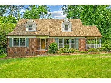 Charming brick home with a lush green lawn, dormer windows, and verdant landscaping at 3449 Parkview Dr, Atlanta, GA 30337
