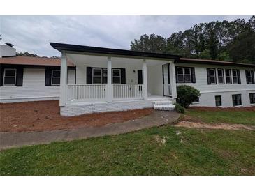 Charming single-story home featuring a covered front porch, white siding, black shutters, and well-maintained landscaping at 871 Cowan Se Rd, Conyers, GA 30094