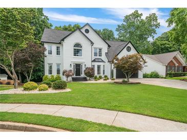 Beautiful two-story home featuring a lush lawn, professional landscaping, and a charming, painted white brick facade at 340 Chandler Ct, Sugar Hill, GA 30518