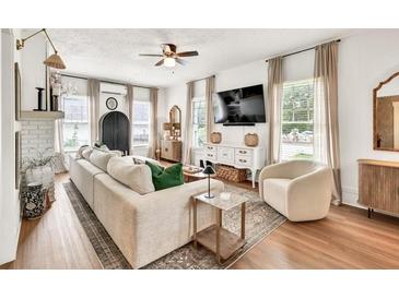 Bright living room featuring a white brick fireplace, a ceiling fan, and an oversized comfy couch at 575 E Main St, Buford, GA 30518