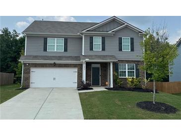 Two-story home features a brick and gray exterior, an attached garage, and a well-manicured lawn at 6827 Chataran Dr, Lithia Springs, GA 30122