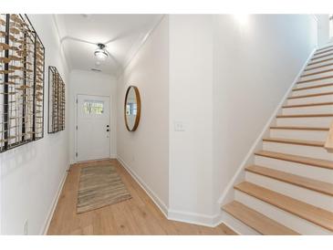 Bright foyer featuring light hardwood floors, white walls, and a staircase leading to the second floor at 436 Carrera Ln, Acworth, GA 30102