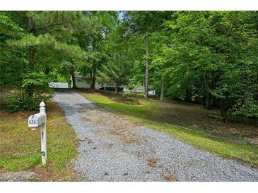 Long gravel driveway leading to a charming home surrounded by lush greenery and a mailbox at the entrance at 6201 Davids Se Way, Acworth, GA 30102