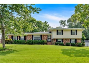 Charming two-story home with a brick and siding facade and a beautifully landscaped front yard under a sunny blue sky at 115 Creek Cir, Stockbridge, GA 30281