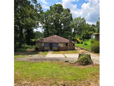 Charming stone home with a unique, rustic exterior and mature trees surrounding the property at 3547 Pleas Dr, Ellenwood, GA 30294