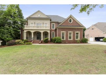 Elegant two-story brick home with a columned front porch and well-manicured lawn and professional landscaping at 1565 Briergate Dr, Duluth, GA 30097