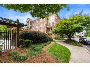 Beautifully landscaped condo exterior featuring brick facade, a pathway, and lush green trees at 1735 Peachtree Ne St # 316, Atlanta, GA 30309