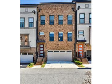 Three-story brick townhome with a two-car garage and steps leading up to front doors on the first level at 1047 Brandsford Nw St, Atlanta, GA 30318