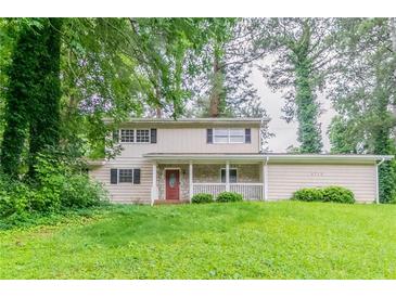 Charming two-story home with a covered front porch and mature trees at 4715 Wildginger Run, Lithonia, GA 30038