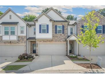 Charming townhome featuring a stone and siding exterior, attached garage, and well-manicured landscaping at 1363 Cooper Springs Rd, Grayson, GA 30017