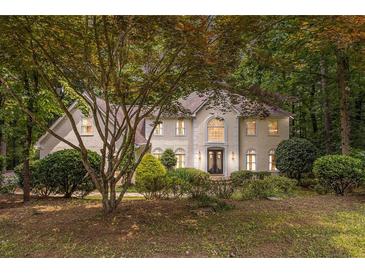 Elegant home featuring manicured landscaping and a charming facade with lush surrounding trees at 8255 Habersham Waters Rd, Atlanta, GA 30350