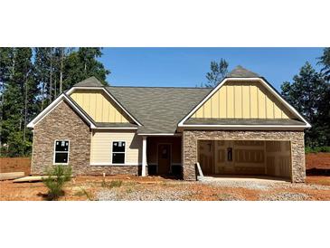 Charming single-story home featuring stone accents, a welcoming front porch, and an attached two-car garage at 490 Charleston Pl, Villa Rica, GA 30180