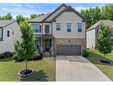 Charming two-story home features a stone and shingle facade, well-manicured lawn, and an attached two-car garage at 4568 Mantova Dr, Buford, GA 30519