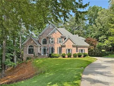 Beautiful two-story brick home with manicured lawn and mature trees at 120 Forest Breeze Cv, Alpharetta, GA 30022