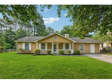 Inviting one-story home featuring a manicured lawn, classic shutters, front porch, and mature landscaping at 3690 Basswood Rd, Snellville, GA 30039
