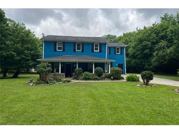Charming two-story home with a lush green lawn and mature trees under a cloudy sky at 5560 Old Bill Cook Rd, College Park, GA 30349