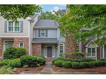 Charming two-story townhome with a well-manicured front yard and brick accents, offers inviting curb appeal at 305 River Glen Dr, Roswell, GA 30075