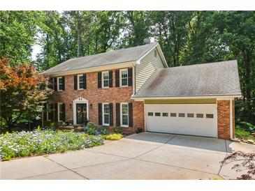 Charming two-story brick home featuring a two-car garage and a beautifully landscaped front yard with vibrant flowers at 3453 Drayton Ne Dr, Roswell, GA 30075
