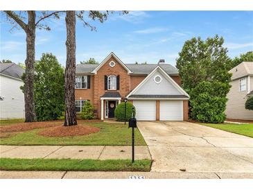 Charming two-story brick home features a manicured front yard, mature trees, and a two-car garage at 1355 Pinebreeze Way, Marietta, GA 30062