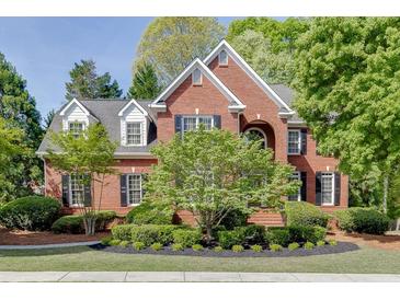Beautiful two-story brick home with a manicured lawn and lush landscaping at 3284 Bakers Mill Ct, Dacula, GA 30019