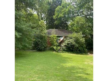 Secluded red brick home amid lush greenery on a spacious lawn, offering privacy and a serene setting at 2105 Rexford Dr, Decatur, GA 30034