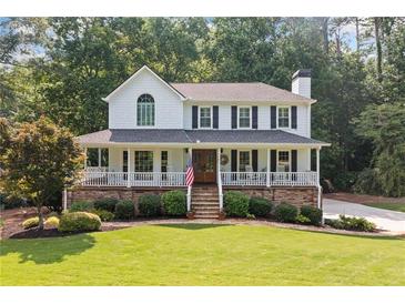 Charming two-story home boasts a welcoming front porch, beautiful stone accents, and a lush green lawn at 226 Nacoochee Dr, Woodstock, GA 30188