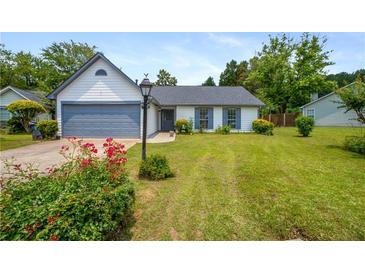 Charming single-story home with a well-manicured lawn, gray garage door, and lovely landscaping at 1055 Kibbe Cir, Lawrenceville, GA 30044