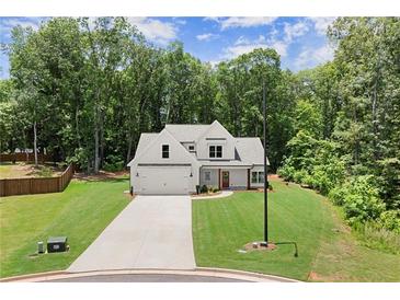 Beautiful new construction home featuring a white exterior, large front lawn, and attached two car garage at 65 Harmony Woods Ln, Dallas, GA 30157