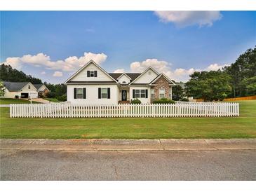 Charming home with a white picket fence, lush green lawn and a mix of stone and siding exterior at 501 Grace Ct, Temple, GA 30179